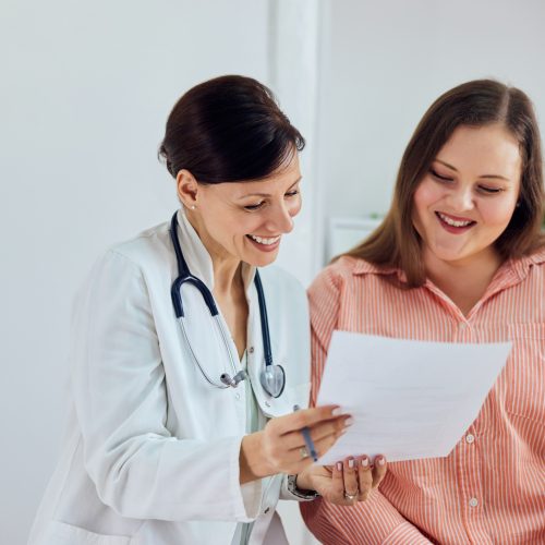Smiling female nutritionist showing progress to a happy patient, also discussing pregnancy option.